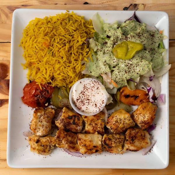 Hala Cafe's chicken shish tawook plate with yellow rice, salad, grilled vegetables, and sauce.