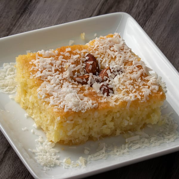 A square piece of Hala Cafe's Mediterranean basbousa cake, topped with shredded coconut and almonds.