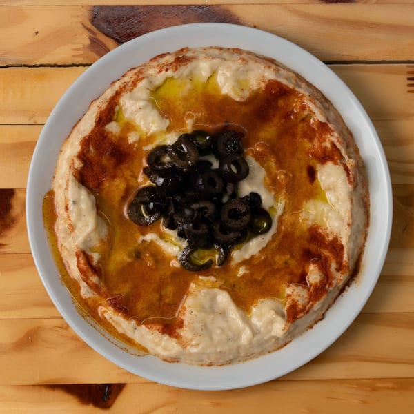 Hala Cafe's creamy hummus, drizzled with olive oil, paprika, and topped with sliced black olives.