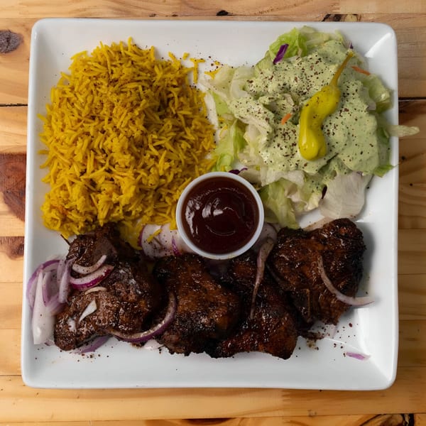 Hala Cafe's Mediterranean dish with yellow rice, salad, dark meat, red onions, and dipping sauce.